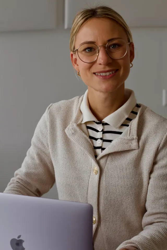 Lisa Marie Schlemm lächelt in die Kamera, sitzt am Laptop